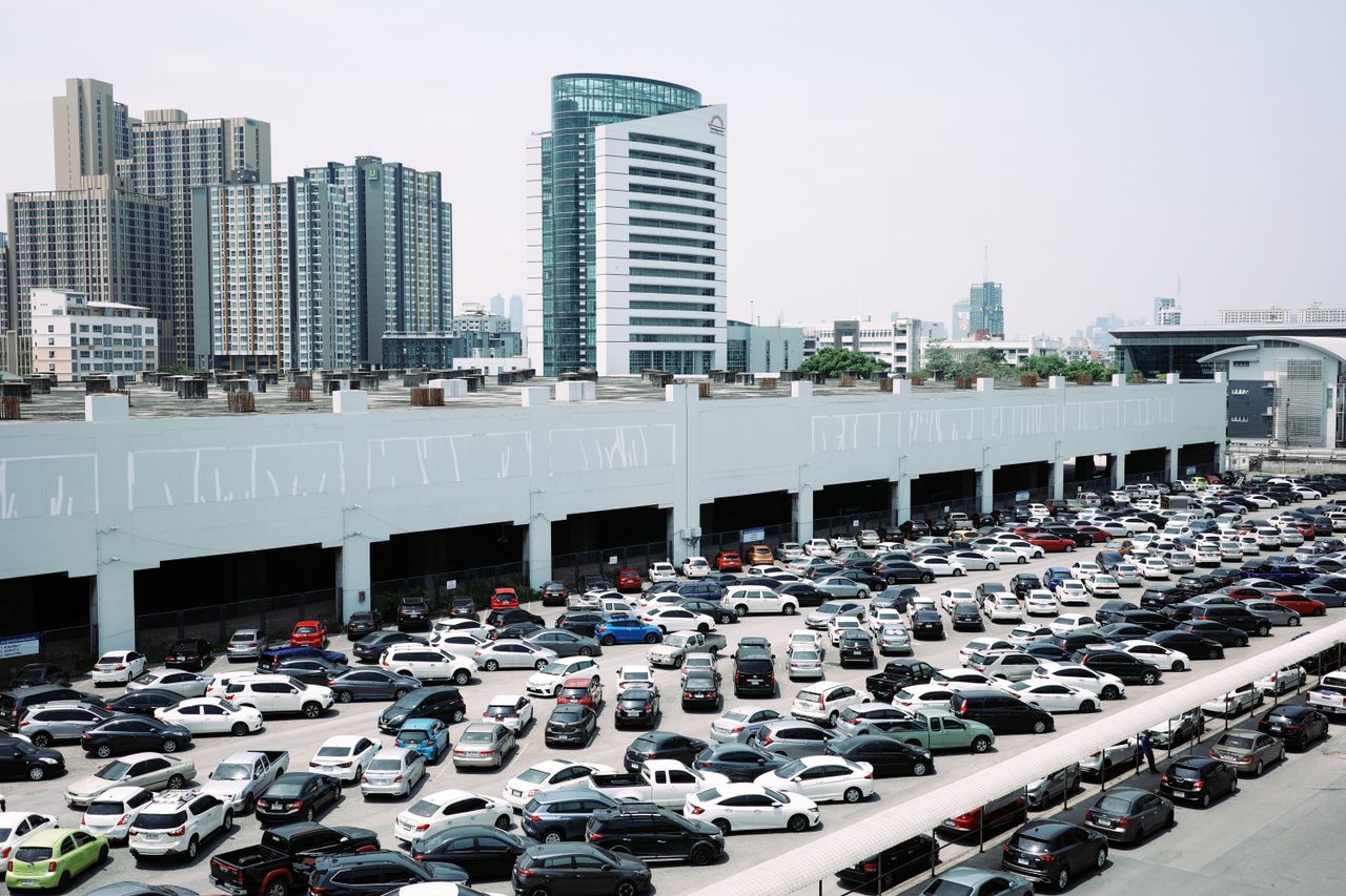 Busy city parking lot with skyscrapers in the background on a clear day.